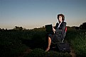 Picture Title - A woman working with her laptop in a country field at the sunset